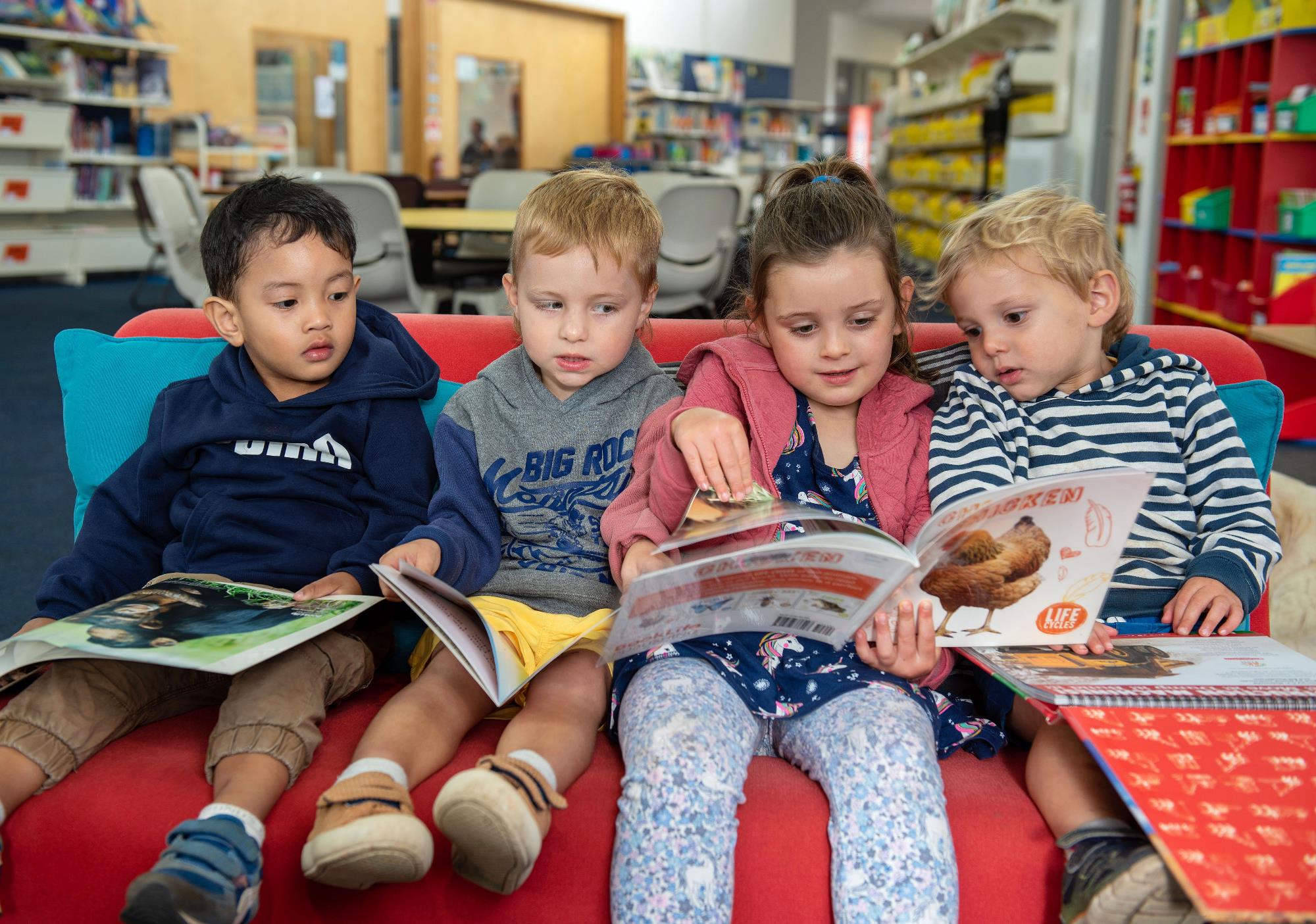 Four children reading books on a couch at Timboon Library